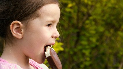 Ein kleines Mädchen isst im Grünen Eis am Stil - Teil 2