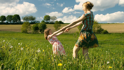 Mutter und Tochter tanzen zusammen im Wind auf einer Frühlingswiese - Teil 2