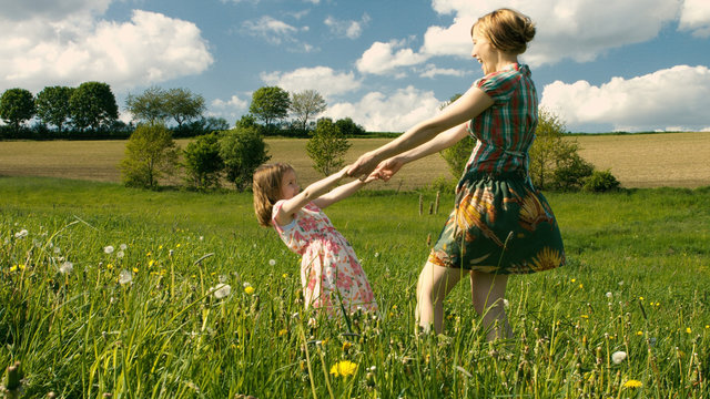 Mutter und Tochter tanzen zusammen im Wind auf einer Fr&uuml;hlingswiese - Teil 2