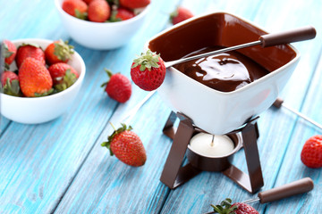 Chocolate fondue with fresh berries on a blue wooden table