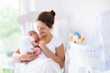 Mother and newborn baby in white nursery