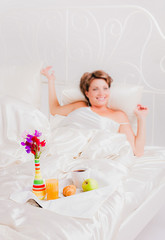 Obraz na płótnie Canvas Happy woman with breakfast on her bed