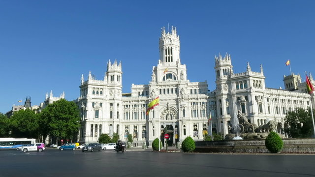 landmark of Cibeles Square in Madrid city Spain Europe with famous sculpture monument fountain of greek goddess and facade of town hall building, car vehicles and bus driving in the street
