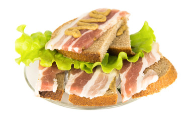 Sandwich with bacon slices, salad and mustard on rye bread on a