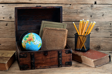 School books with globe and pencils in the old chest
