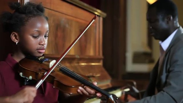 Father playing piano and daugther playing fiddle