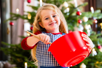 Mädchen backt in der Küche Kekse vor Weihnachtsbaum 