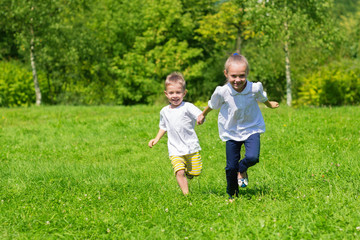 Fototapeta premium Girl and boy running on the grass