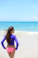 Fototapeta na wymiar Woman relaxing on beach in sun protection swimwear