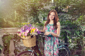 Girl with a vintage bicycle and a basket of flowers