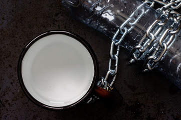 Mug and plastic bottle of water with remains of steel chain