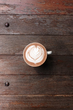 cup of latte art coffee on wooden background