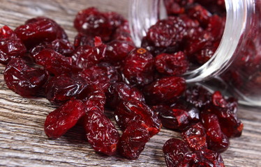 Cranberries spilling out of glass jar on wooden table