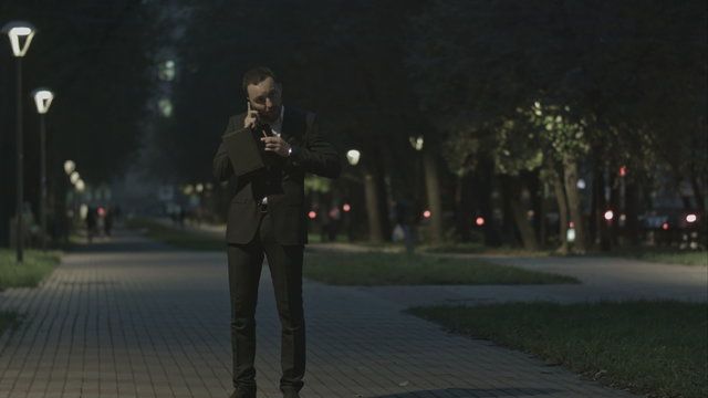 Adult bearded business man talking on cell phone while standing in the city street, business man have conversation, stylish hipster in suit using cellphone