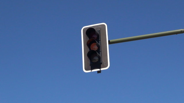orange blinking traffic light in Madrid city Spain Europe on blue sky
