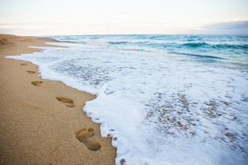 footprints on sandy beach and sea wave