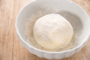Fototapeta na wymiar Gnocchi dough in white ceramic bowl on wood