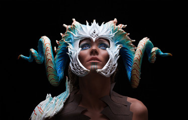 Fantasy concept of a young girl,strong brave warrior,wearing a helmet - mask with horns on head with corals with dots - obrazy, fototapety, plakaty