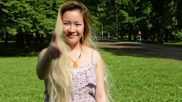 young attractive asian woman press the flesh in the park - close up