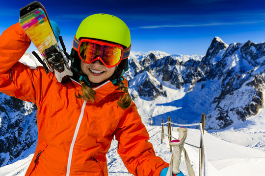Portrait of young girl with ski, in background panorama of snowy Alps Mountains