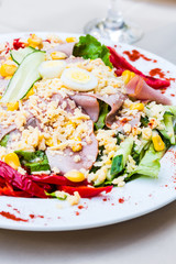 green salad with ham, egg, corn and pepper on the white tableclo