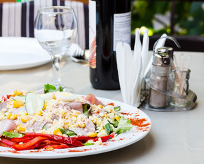 green salad with ham, egg, corn and pepper on the white tableclo