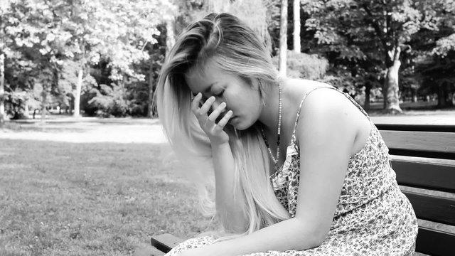 young asian attractive sad woman sits on the bench in the park - black and white