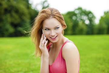 Beautiful red-haired smiling young woman talking on a cell phone
