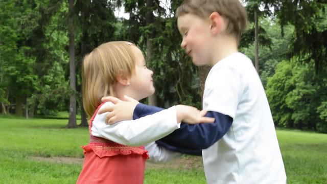 children (siblings - boy and girl) give a kiss in park