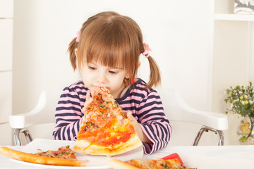 Little girl with pigtails eating pizza