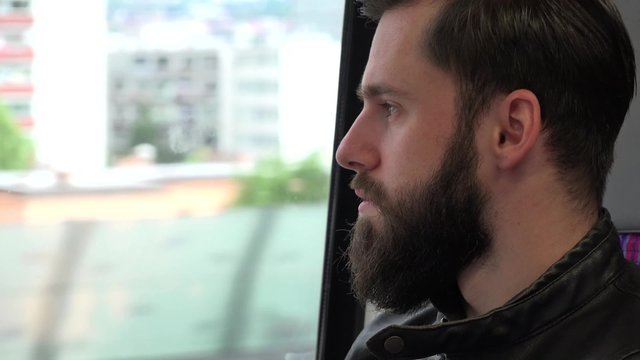 young handsome hipster man travel by train and looks out of the window - city - closeup