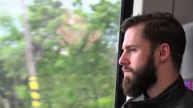 young handsome hipster man travel by train and looks out of the window - city - closeup