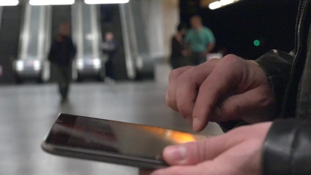 young handsome hipster man works on tablet - subway station (escalators) - closeup