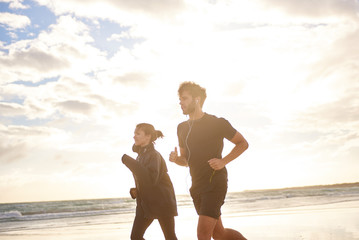 Joggers running together on the beach with sun flare
