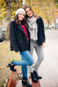 Cute best friend girls standing on a bench smiling