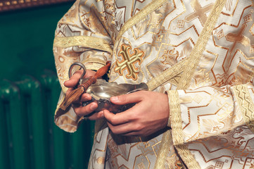 silver vessel with holy water in the priest's hands