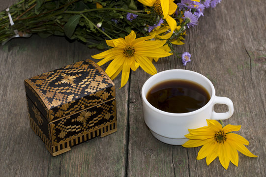 cup of coffee, wild flowers, casket and yellow flower, still lif