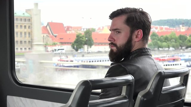 young handsome hipster man travel by tram - city - building in the background
