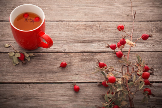 cup of tea with hip roses, on wooden table