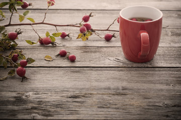 cup of tea with hip roses, on wooden table