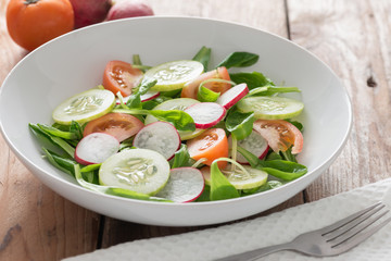 Spring salad from cucumbers, radish and tomato on white plate.