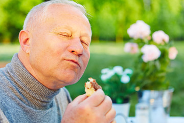 Alter Mann isst Kuchen im Garten