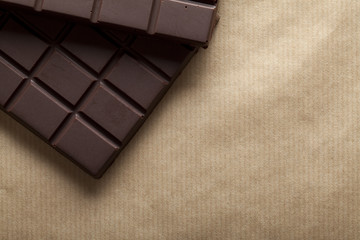 Dark chocolate bar on brown paper background