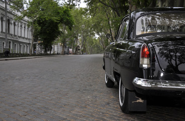 Retro car. Black old auto on the brick road