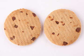 Two chocolate chip biscuits, in  white background.