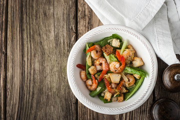 Caesar salad with prawns on the wooden table  top view