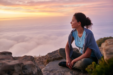 Naklejka na ściany i meble Woman looking out at the morning clouds from a mountain top