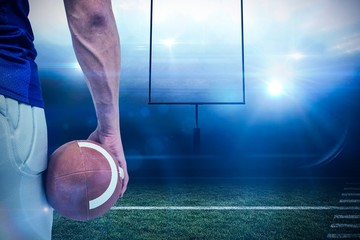 Composite image of american football player holding ball