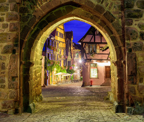Fototapeta na wymiar View of Riquewihr, Alsace, France, through city wall gate at nig
