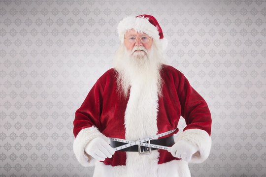 Composite image of santa claus measures his belly